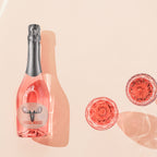 Pink bottle of Loose Moose sparkling wine with decorative glassware on a beige background